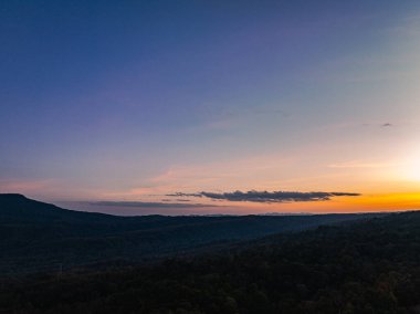 Dağların üstündeki renkli gökyüzü ile günbatımının havadan görünüşü 