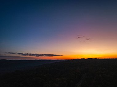 Dağların üstündeki renkli gökyüzü ile günbatımının havadan görünüşü 