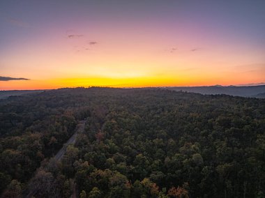 Dağların üstündeki renkli gökyüzü ile günbatımının havadan görünüşü 
