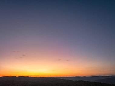 Dağların üstündeki renkli gökyüzü ile günbatımının havadan görünüşü 