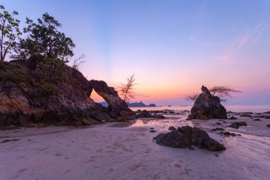 Güzel bir akşam güneşi parlıyor denizin üzerinde, cennetin kumsalında.