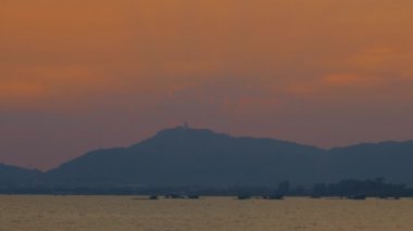 Gün batımında, Buda turuncu gökyüzüne karşı siluet oluşturur ve güzel bir manzara yaratır. Hafif bir esinti çevreleyen ağaçların yapraklarını hışırdattı, beraberinde doğanın uzak sesini getirdi..