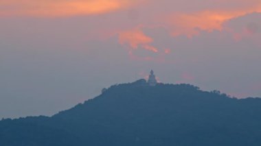 Gün batımında, Buda turuncu gökyüzüne karşı siluet oluşturur ve güzel bir manzara yaratır. Hafif bir esinti çevreleyen ağaçların yapraklarını hışırdattı, beraberinde doğanın uzak sesini getirdi..