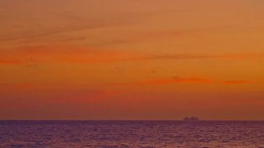 Altın yaz günbatımında okyanusta seyahat eden bir gemi.