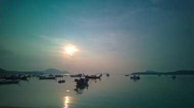 Rawai sahilindeki balıkçı teknelerinin üzerinde gün doğumunda mavi bulutların hızlanması.