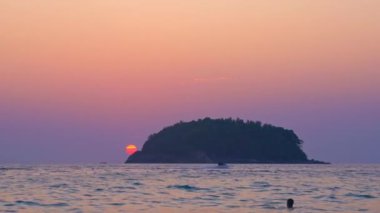 Güzel kırmızı güneş adanın arkasında batıyor. Renkli romantik gökyüzü günbatımı sahnesi. Gün batımında güzel altın gökyüzü Kata sahilinde Phuket 'te Pu adası üzerinde doğa ve seyahat konsepti..