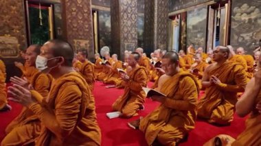 Bangkok, Tayland - 10 Nisan 2024: Keşişler Wat Bowonniwet Vihara şapelinde ana Buda resmi önünde dua ediyorlar.