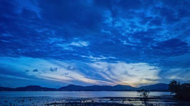 Gün batımında mavi gökyüzünde hareket eden mavi bulutlar dağ sırasının üstünde..