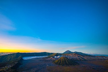 Güneşin doğuşunda mavi gökyüzü olan Bromo volkanları 