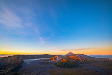 Güneşin doğuşunda mavi gökyüzü olan Bromo volkanları 