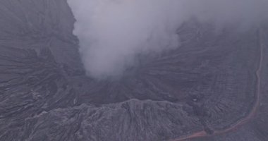 Bromo volkanik kraterinden yükselen beyaz dumanın hava görüntüsü yavaşça
