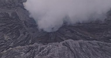 Bromo volkanik kraterinden yükselen beyaz dumanın hava görüntüsü yavaşça