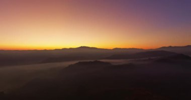 Hava manzarası, sabah güneşinin sisli denizin üzerindeki altın ışığı. Vadide sakin bir akşam atmosferi oluşur. Dağ sırasının renkli renkleri.