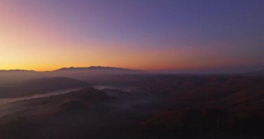 Hava manzarası, sabah güneşinin sisli denizin üzerindeki altın ışığı. Vadide sakin bir akşam atmosferi oluşur. Dağ sırasının renkli renkleri.