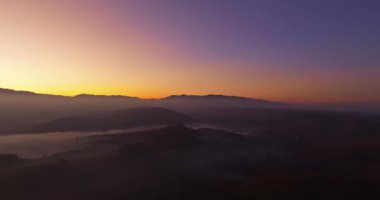 Hava manzarası, sabah güneşinin sisli denizin üzerindeki altın ışığı. Vadide sakin bir akşam atmosferi oluşur. Dağ sırasının renkli renkleri.