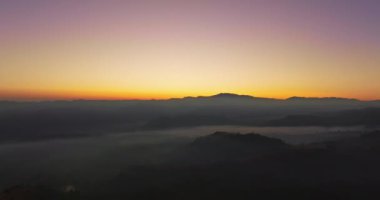Hava manzarası, sabah güneşinin sisli denizin üzerindeki altın ışığı. Vadide sakin bir akşam atmosferi oluşur. Dağ sırasının renkli renkleri.