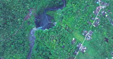 Görkemli bir şelalenin, yemyeşil bir uçurumdan, sisli bir havuza dökülüşünün havadan görüntüsü. Canlı yeşillik ve dramatik düşüş çarpıcı bir doğal manzara yaratır.