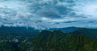 Doğu Java 'da Kabut Pelangi Şelalesi havadan görünüyor. Şelale deresi uzun bir yoldan dağ geçidine akar. Yukarıda köylülerin evi bulunur. Yeşil dağdaki ormanların bolluğu.