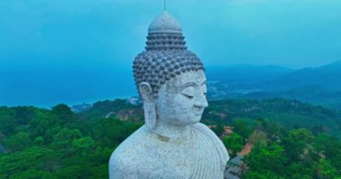 Etkileyici ve dingin bir Buda heykeli, huzur ve maneviyatı temsil eden, dimdik ayakta duruyor. Heykel yemyeşil ile çevrili, berrak bir gökyüzüne karşı huzur verici varlığını arttırıyor..