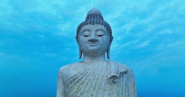Gökyüzü görüşü Phuket Büyük Buda heykeli, huzur ve maneviyatı simgeleyen bir dağın tepesinde heybetlidir. Buda heykeli, mavi gökyüzünün altındaki yemyeşil ağaçlarla çevrilidir.