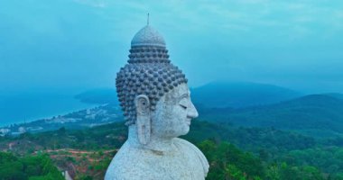 Havadan bakıldığında Phuket büyük Buda heykeli dağın tepesinde huzur ve maneviyatı sembolize ediyor. Buda heykeli mavi gökyüzünün altında yemyeşil ağaçlarla çevrili.