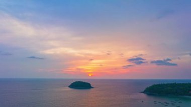 Adanın yukarısındaki günbatımında havadan hiperhız manzarası güzel gökyüzü. Güneş, Kata plajı Phuket Tayland 'daki Pu adasının yanından denize batıyor. hisse senedi video seyahat kavramı. 