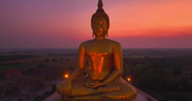 Güzel bir günbatımında arka planda altın bir Buda 'nın çarpıcı görüntüsü