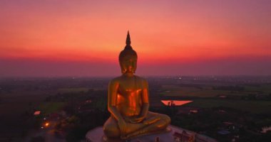 Hava manzarası arka planda büyük altın bir Buda ile güzel bir gün batımını gösteriyor.