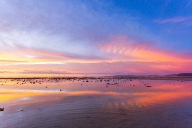 Pling Adası 'nın yukarısındaki Nayang plajı Phuket' te gün batımında inanılmaz renkli bulut. Huzurlu bir alacakaranlık sahnesi baş döndürücü bir eğimle gece çökerken mor renkten ılık turuncuya dönüşüyor..