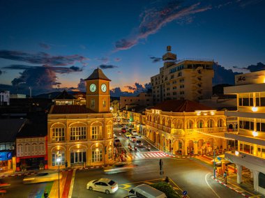 Batan güneşin yumuşak parıltısıyla aydınlanan yükselen bir bulutun yer aldığı çarpıcı bir şehir manzarası. Sahne modern ve tarihi mimarinin bir karışımını sergiliyor.