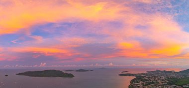 Phuket tepelerinin üzerinde canlı bir günbatımının nefes kesici hava manzarası. Tepenin tepesindeki Phuket Büyük Buda. Gökyüzü, günün son ışığı olarak koyu portakallar, kırmızılar ve morlarla boyanır.