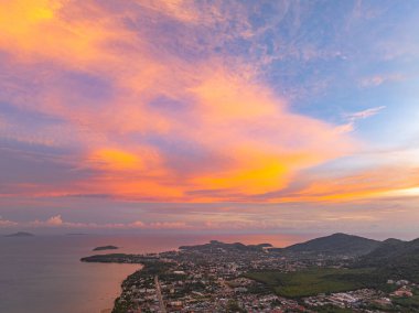 Gün batımında yumuşak pastel renklerle yıkanan Phuket adalarının hava manzarası. Aşağıdaki sakin deniz adalarla dolu, yukarıdaki gökyüzü ise narin pembe ve turuncu bulutlarla boyanmış..