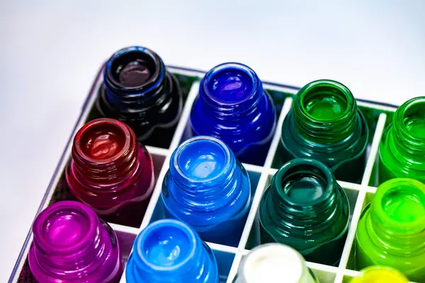 stock image A vibrant display of various colored ink bottles arranged in a grid pattern, showcasing a spectrum of bright and vivid hues. The image highlights the rich and diverse palette of colors for art.