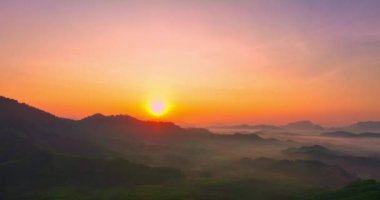 Sabah dağların üzerinden yükselen altın güneşin havadan görünüşü