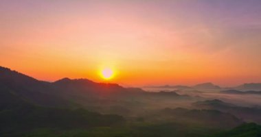 Sabah dağların üzerinden yükselen altın güneşin havadan görünüşü