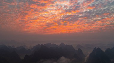 Güneşin doğuşuyla dağların üzerinden inanılmaz renkli gökyüzü manzarası. Vadiler ve nehirlerle benekli sakin manzara, parlayan bulutlara karşı büyüleyici bir zıtlık yaratır. Harika bir yer.