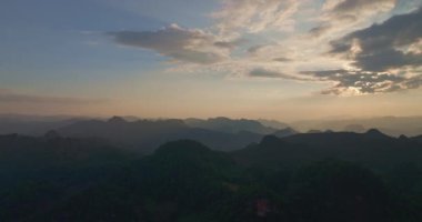 Hava görüntüleme videosu. Güneş dağlardaki bulutların arasından parlıyor. 