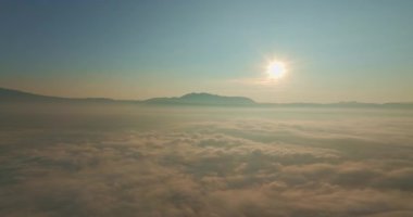 Sis denizinde hava hiper kayması baş döndürücü bir gün doğumu. Güneş, sis denizinin üzerinde altın gibi parlıyor. Işığı, dağınık bulutların arasından süzülüyor. Doğanın güzelliği yukarıdan. 