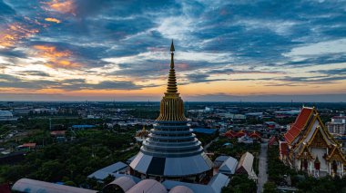 Hava Wat Ketmadi Sriwararam perspektifi bulutlu mavi gökyüzü altında şehir ve kırsal alanlarla çevrili büyüleyici bir Tayland tapınak kompleksi sergiliyor..