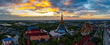 Hava Wat Ketmadi Sriwararam perspektifi bulutlu mavi gökyüzü altında şehir ve kırsal alanlarla çevrili büyüleyici bir Tayland tapınak kompleksi sergiliyor..