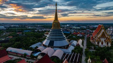 Hava Wat Ketmadi Sriwararam perspektifi bulutlu mavi gökyüzü altında şehir ve kırsal alanlarla çevrili büyüleyici bir Tayland tapınak kompleksi sergiliyor..