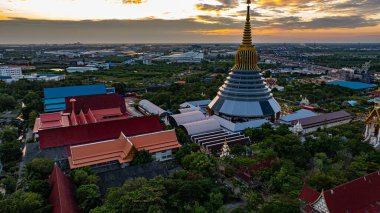 Hava Wat Ketmadi Sriwararam perspektifi bulutlu mavi gökyüzü altında şehir ve kırsal alanlarla çevrili büyüleyici bir Tayland tapınak kompleksi sergiliyor..