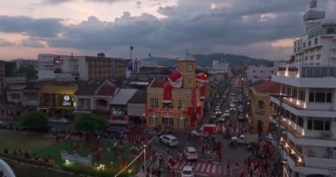 Phuket, Tayland-Aralık, 25. 2024: Büyük Noel Baba ve Noel Anne süslemeleriyle süslenmiş tarihi sarı saat kulesinin olduğu canlı bir sahne dramatik bir akşam gökyüzü. Mutlu yıllar 2024