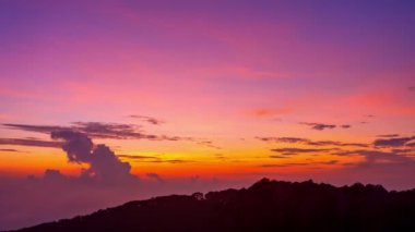 Yoğun bir ormanın üzerinde zaman aşımına uğrayan gün doğumu, dalgalı bulutlar ve sislerin arasından altın bir parıltı saçıyor. Bu büyüleyici sahne sıcak ve serin tonlarla harmanlanarak dramatik ve sakin bir doğal manzara yaratır..