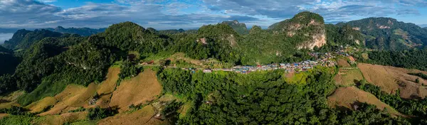 Güneşin erken saatlerinde sisli vadileri ve arkasında dramatik tepeleri olan bir dağ köyünün nefes kesici hava manzarası. Sahne, kırsal yaşamın dingin güzelliğini yakalıyor..  