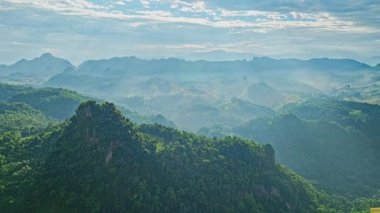  Güneşin tepedeki havadan görünüşü dağın tepelerindeki güneş vadide parlıyor. Bulutlu gökyüzü ve çevreleyen tepeler bu manzaranın huzurlu atmosferini arttırır..