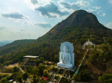 Görkemli bir Buda heykeli yemyeşil tepeler ve doğal ışık arasında meditasyon yapıyor. Bu huzurlu yer, kutsal mimarinin ve doğal güzelliğin uyumunu sergiliyor. dağ arkaplanı