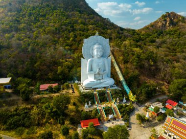 Görkemli bir Buda heykeli yemyeşil tepeler ve doğal ışık arasında meditasyon yapıyor. Bu huzurlu yer, kutsal mimarinin ve doğal güzelliğin uyumunu sergiliyor. dağ arkaplanı