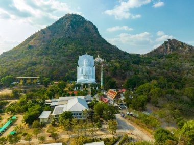 Görkemli bir Buda heykeli yemyeşil tepeler ve doğal ışık arasında meditasyon yapıyor. Bu huzurlu yer, kutsal mimarinin ve doğal güzelliğin uyumunu sergiliyor. dağ arkaplanı