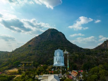 Görkemli bir Buda heykeli yemyeşil tepeler ve doğal ışık arasında meditasyon yapıyor. Bu huzurlu yer, kutsal mimarinin ve doğal güzelliğin uyumunu sergiliyor. dağ arkaplanı